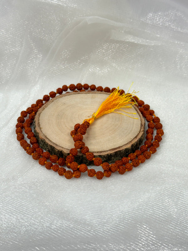A traditional 108-bead 5 Mukhi Rudraksha Mala featuring natural brown seeds with five distinct faces, finished with a decorative red silk tassel