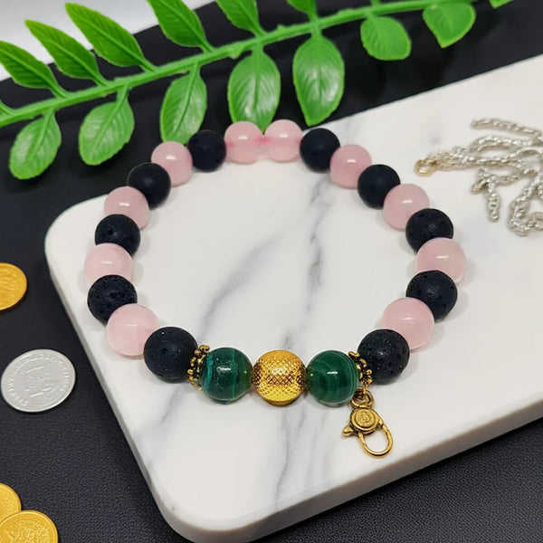 Bracelet with multicolored beads on a marble surface with green leaves in the background