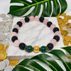 Multicolored beaded bracelet on a marble surface with coins and leaves in the background