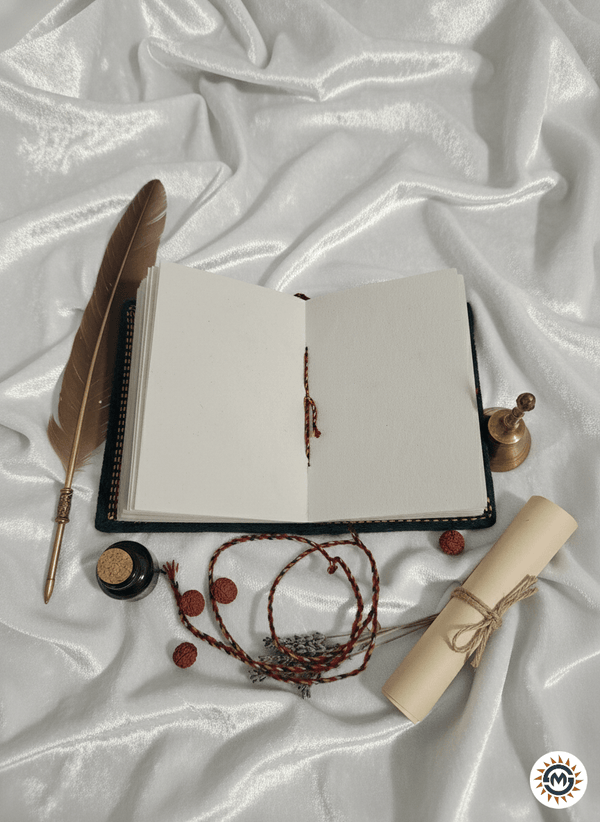 Open notebook with a feather pen, inkwell, and decorative items on a textured white surface