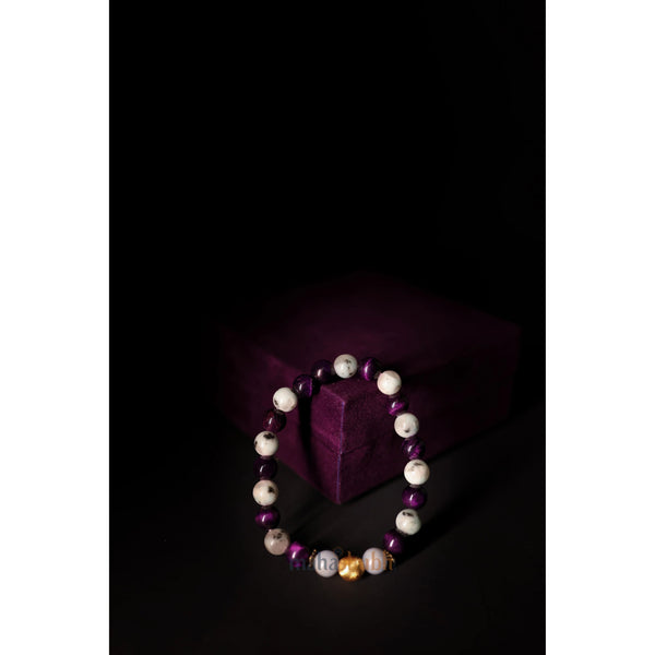 Beaded bracelet with purple, white, and gold beads on a dark background
