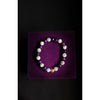 Bracelet with purple and white beads on a purple square background