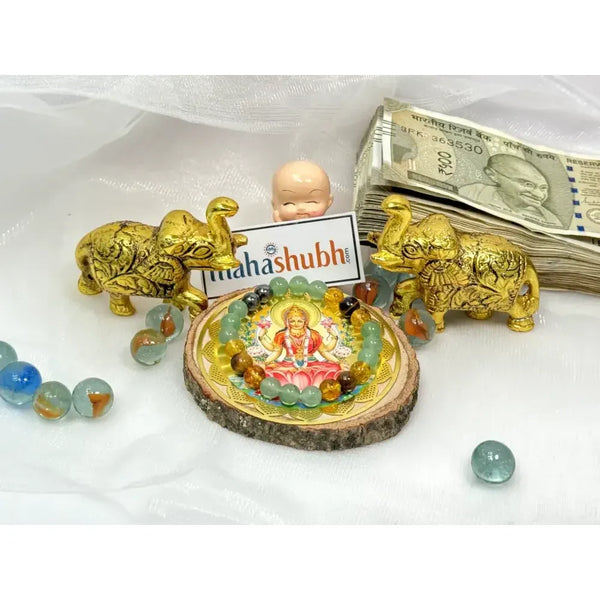Decorative items including gold elephants, a small statue, and money on a white surface with 'mahashubh' branding.
