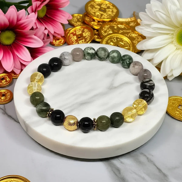 Bracelet with multicolored beads on a marble surface with flowers and gold coins.