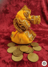 Yellow fabric pouch with gold trim on a red background with gold coins.
