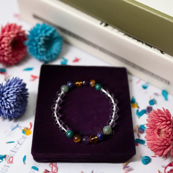 Colorful beaded bracelet on a purple cushion with decorative flowers in the background