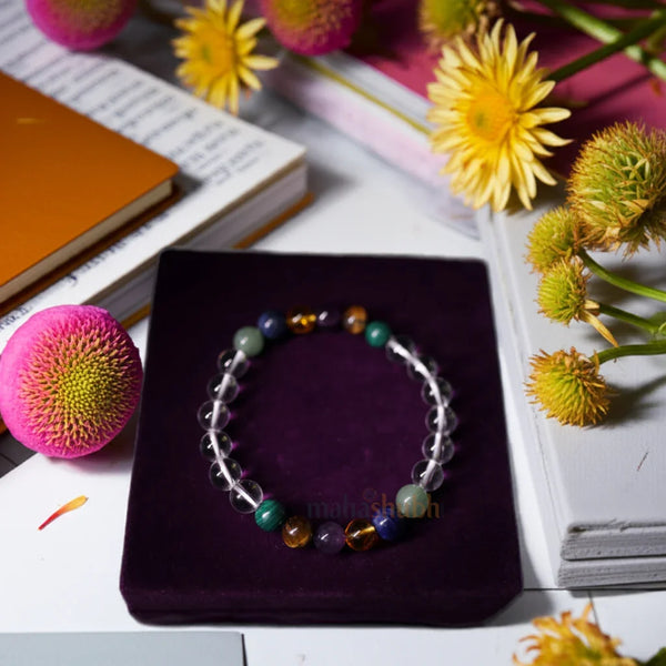 Colorful beaded bracelet on a purple stand with flowers and books in the background