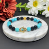 Beaded bracelet with gold hamsa charm on a marble coaster with flowers in the background