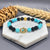 Bracelet with turquoise and black beads on a marble stand with wheat stalks in the background