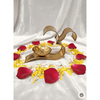 brass Om diya candle holder surrounded by red rose petals and yellow-white flower petals on white satin