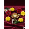 Brass diya oil lamp surrounded by red roses, yellow marigolds, and white daisies on red velvet fabric