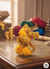 Decorative yellow and gold item on a wooden surface with colorful fabrics in the background