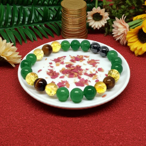 Colorful beaded bracelet on a white plate with flowers, surrounded by green leaves and gold coins.