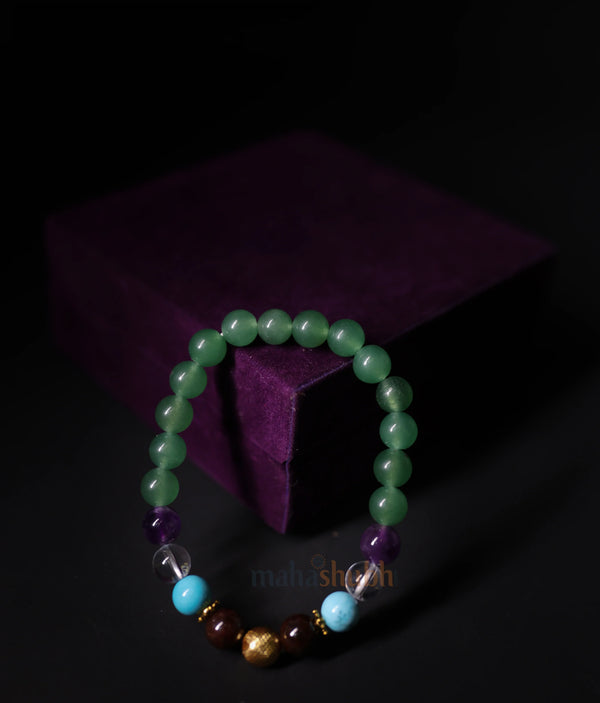 Beaded bracelet with green, purple, and gold beads on a dark background