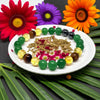 Colorful beads and herbs on a white plate with flowers and leaves in the background