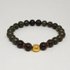 Bracelet with dark beads and a gold ball on a light gray background