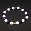 Beaded bracelet with white, purple, and gold beads on a dark background