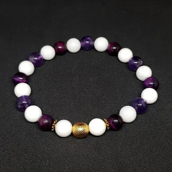 Beaded bracelet with white, purple, and gold beads on a dark background