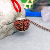 Close-up of a natural five mukhi rudraksha pendant with silver caps on red thread, set against white stone and spiritual decor