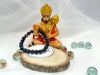 A black banded bracelet displayed next to a figure of a deity, possibly indicating the spiritual or protective properties associated with the product.