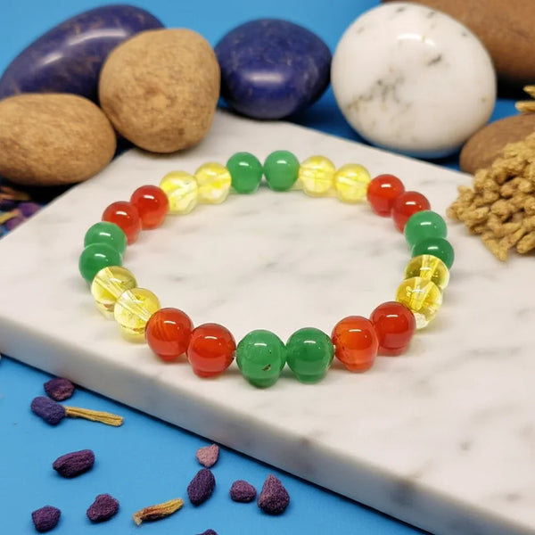Colorful beaded bracelet on a marble surface with stones and plants in the background