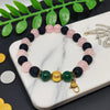 Bracelet with multicolored beads on a marble surface with green leaves in the background