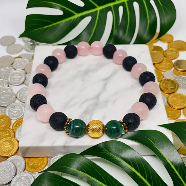 Multicolored beaded bracelet on a marble surface with coins and leaves in the background