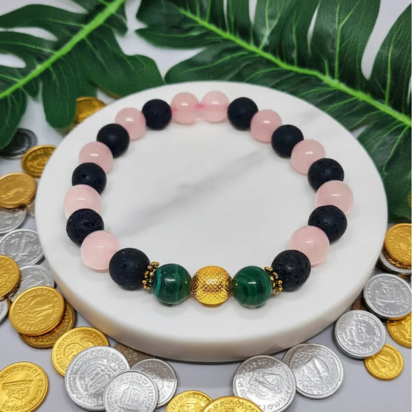 Colorful beaded bracelet on a white surface with coins and green leaves in the background