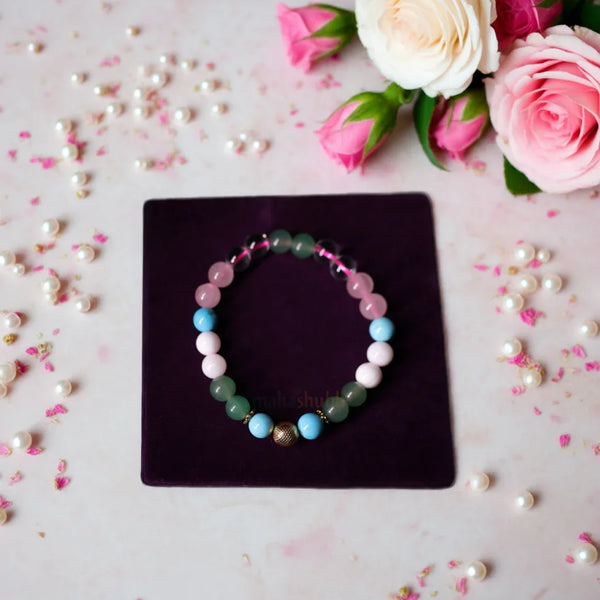 Multicolored beaded bracelet on a dark surface with pink roses and pearls around
