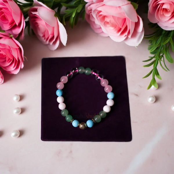 Multicolored beaded bracelet on a dark purple card with pink roses and green leaves in the background.