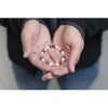 Person holding a beaded bracelet in their hands against a neutral background