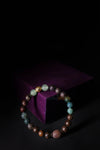 Multicolored beaded bracelet on a dark background with a purple cube