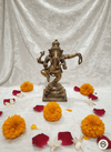 Bronze statue of a deity surrounded by marigold flowers on a white fabric background