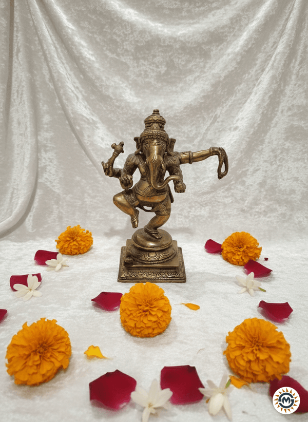 Bronze statue of a deity surrounded by marigold flowers on a white fabric background