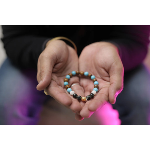 Hands holding a bracelet with beads in the shape of a heart against a blurred background