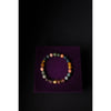 Multicolored beaded bracelet on a purple stand against a black background