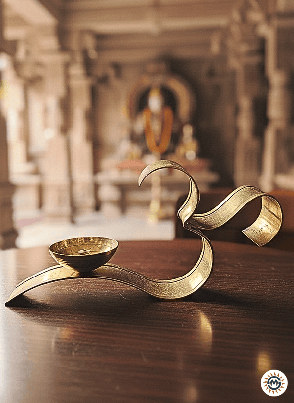 Brass OM diya lamp on wooden table inside traditional Indian temple with blurred deity statue in background