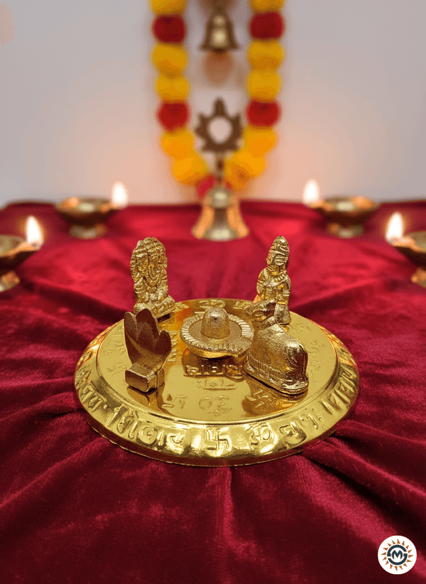 Golden Hindu puja plate with Lingam, Nandi, deities on red velvet cloth, surrounded by lit oil lamps and marigold garland