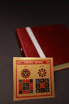 Sacred Vyapar Vriddhi Yantra for business success and wealth. The image shows a flat square metallic plate with intricate Vedic geometry and numerical codes designed to attract positive energy into a workspace or office.