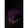 Beaded bracelet on a purple velvet box against a black background