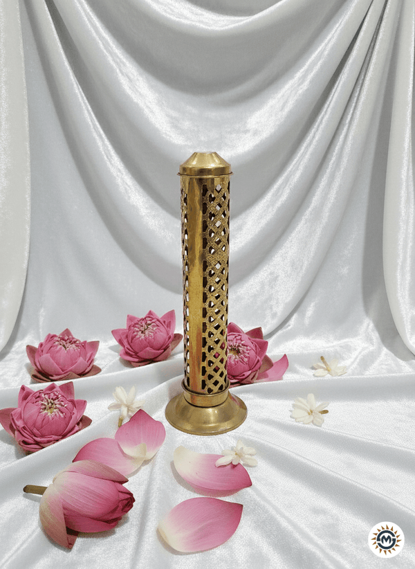 Decorative brass incense burner with pink lotus flowers on a white fabric background