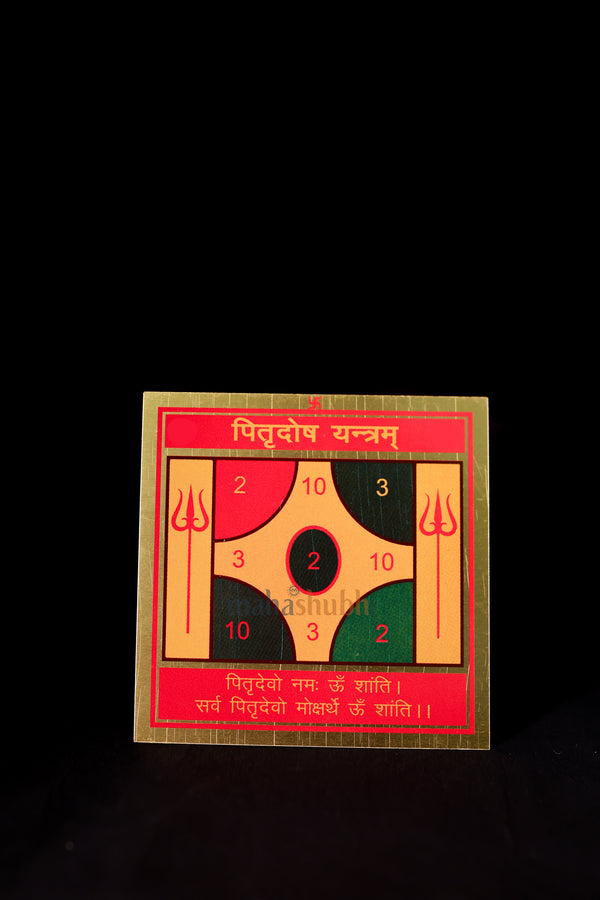 A colorful Pitra Dosh Yantra card with geometric patterns and Sanskrit text, placed against a black background.