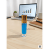 Blue rollerball bottle with gold cap on a desk next to a laptop and notebook.