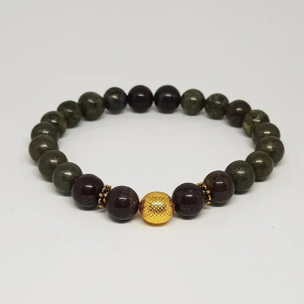 Bracelet with dark beads and a gold ball on a light gray background